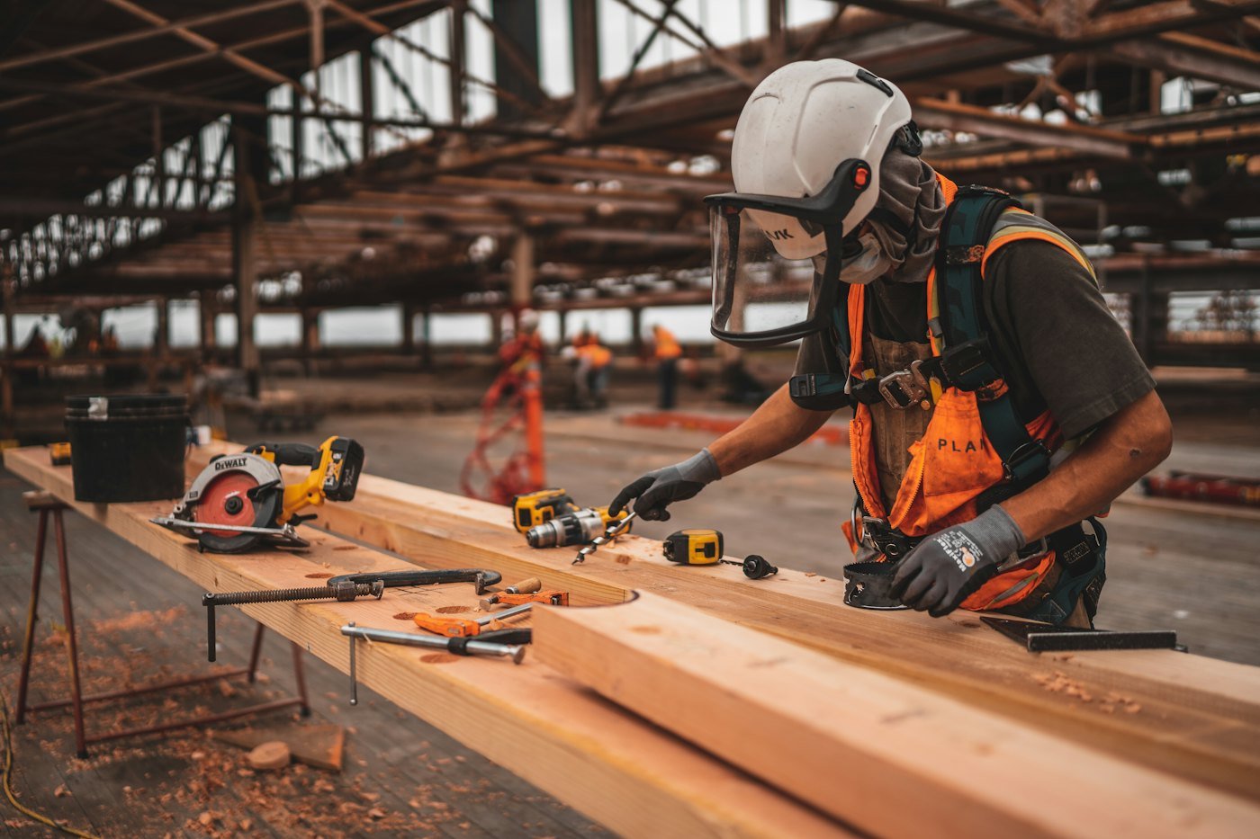 Artisan en équipement de protection travaillant le bois sur un établi de chantier
