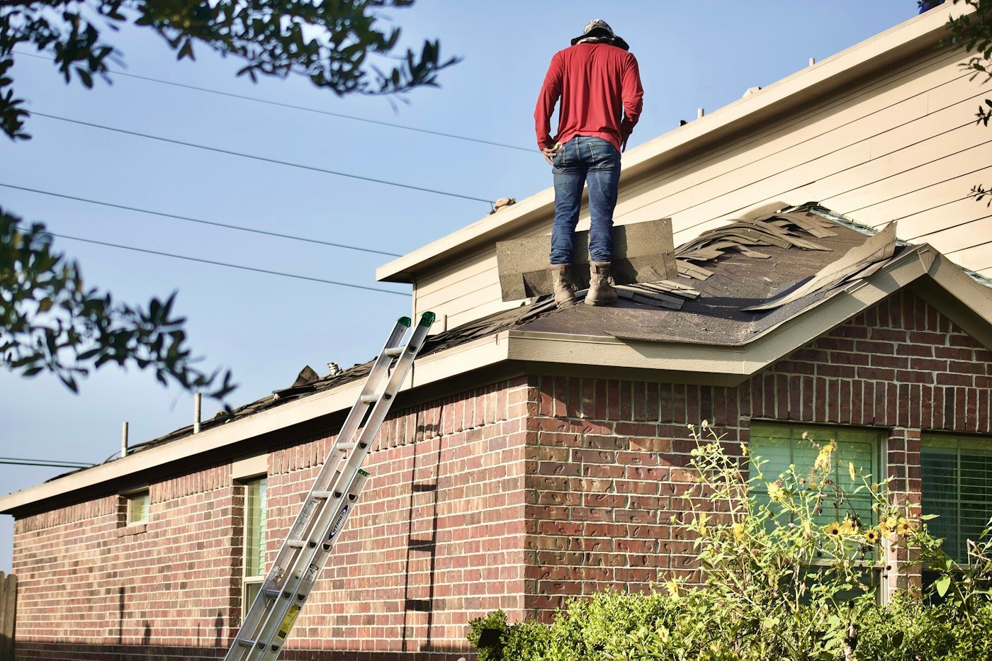 Artisan intervenant sur une toiture de maison en briques